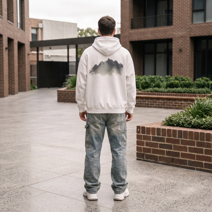 Mountain Watercolor Hoodie back print worn in a city courtyard